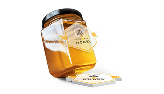 Wild raw honey product label being placed on a glass jar