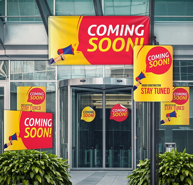 Yellow and red coming soon signs and banners displayed in front of a mall